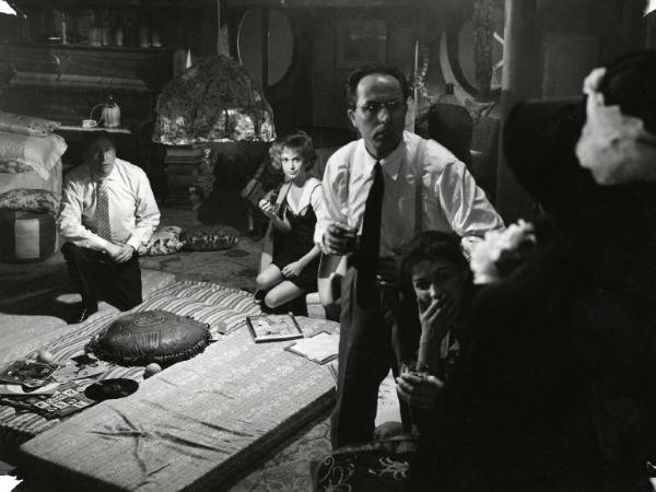 Scena del film "Il disordine" - Regia Franco Brusati, 1962 - Attori non identificati guardano con apprensione una donna con un cappello ripresa di spalle.