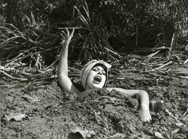 Scena del film "Divorzio all'italiana" - Regia Pietro Germi, 1961 - Daniela Rocca completamente coperta di terra, ha la bocca spalancata e agita un braccio.