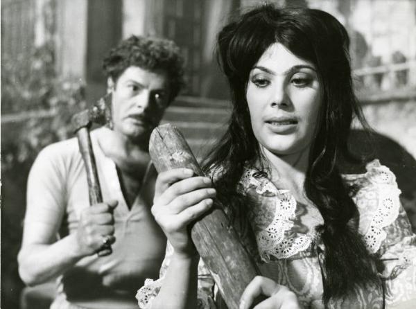 Scena del film "Divorzio all'italiana" - Regia Pietro Germi, 1961 - Daniela Rocca in primo piano stringe un ciocco di legno, Marcello Mastroianni, dietro di lei, brandisce un'accetta.