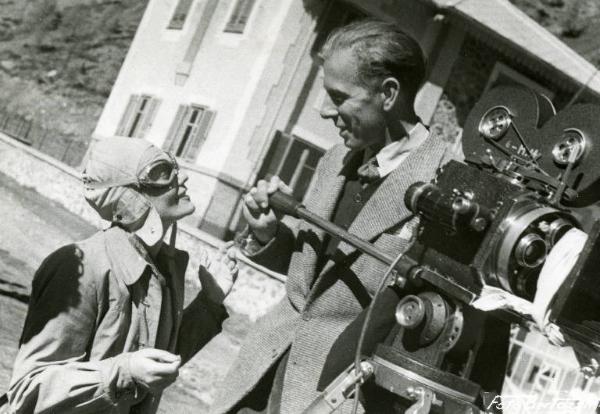Sul set del film "Documento Z 3" - Regia Alfredo Guarini, 1942 - Mezza figura di Isa Miranda con casco e occhiali da aviere che sorride a Gábor Pogány, direttore della fotografia, in piedi sul piedistallo della macchina da presa.