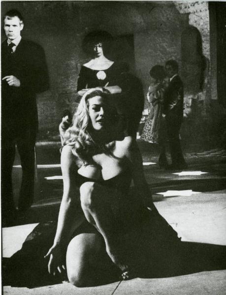 Scena del film "La dolce vita" - Regia Federico Fellini, 1960 - Anita Ekberg inginocchiata. Dietro di lei, in piedi, attori e attrici non identificati.