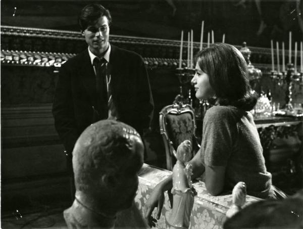 Scena del film "I dolci inganni" - Regia Alberto Lattuada, 1960 - Piano medio frontale di Jean Sorel, con le mani in tasca. Catherine Spaak seduta, di profilo, appoggia i gomiti sullo schienale di un divanetto.