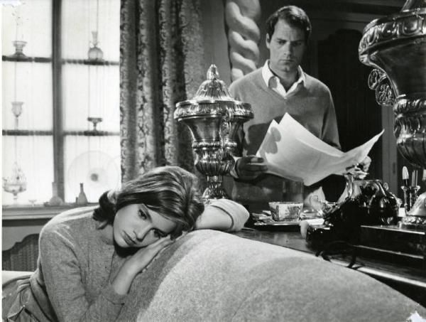 Scena del film "I dolci inganni" - Regia Alberto Lattuada, 1960 - Catherine Spaak, seduta su un divano, poggia le braccia e la testa, sullo schienale. Dietro di lei, Christian Marquand, in piedi, regge dei fogli e la osserva.