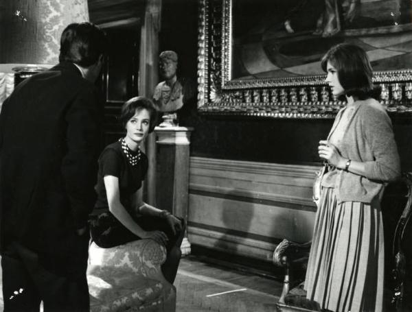 Scena del film "I dolci inganni" - Regia Alberto Lattuada, 1960 - In un salotto elegante, Jean Sorel, di spalle, si rivolge verso Antonella Erspamer, seduta sul bracciolo di un divano. A destra, Catherine Spaak, in piedi, li guarda.