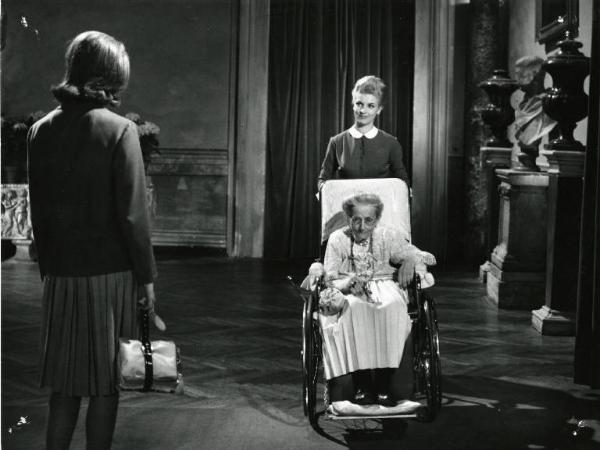 Scena del film "I dolci inganni" - Regia Alberto Lattuada, 1960 - Catherine Spaak in piedi, di spalle, a sinistra. Di fronte a lei un'anziana signora in carrozzella viene spinta da una cameriera.