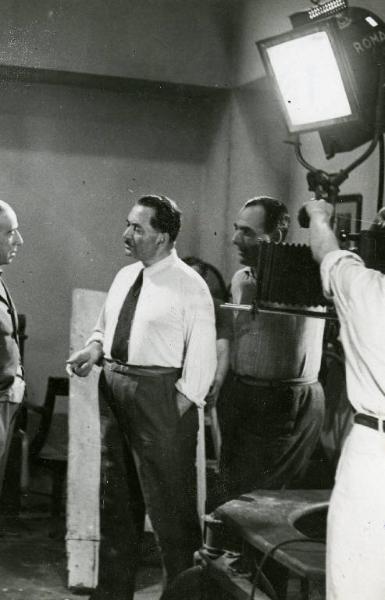 Sul set del film "Il dottor Antonio" - Regia Enrico Guazzoni, 1937 - Enrico Guazzoni da le ultime disposizioni a Lamberto Picasso ed Ennio Cerlesi durante le riprese di una scena del film.