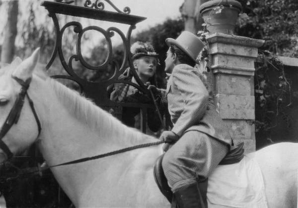 Scena del film "La donna perduta" - Regia Domenico Gambino, 1940 - Luisella Beghi, attraverso un cancello, si protende verso un attore non identificato, a cavallo.