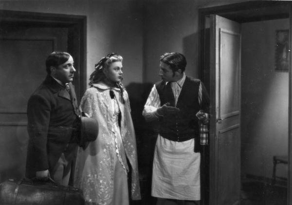 Scena del film "La donna perduta" - Regia Domenico Gambino, 1940 - In una stanza, piano americano di Tino Scotti mentre apre la porta a Luisella Beghi e Carlo Campanini.
