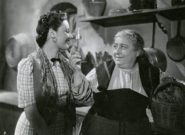 Scena del film "Le due madri" - Regia Amleto Palermi, 1938 - A destra, Bella Starace Sainati sorride e con l'indice della mano destra tocca il mento di Maria Denis, sulla sinistra.