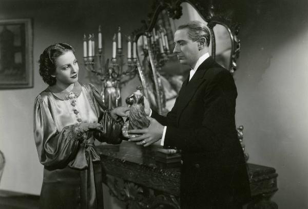 Scena del film "Due occhi per non vedere" - Regia Gennaro Righelli, 1939 - Romolo Costa, di profilo a destra, porge una piccola statua a Loretta Vinci, a sinistra.