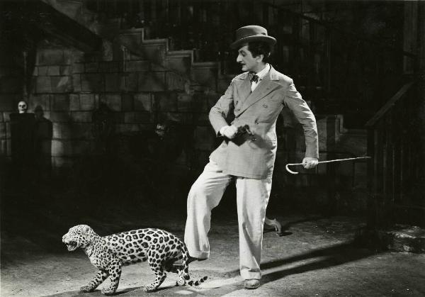 Scena del film "Duetto vagabondo" - Regia Guglielmo Giannini, 1938 - Enrico Viarisio, con un bastone nella mano sinistra, dà un calcio a un cucciolo di leopardo.