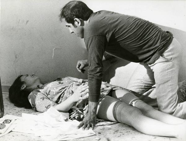 Scena del film "Ecco noi per esempio..." - Regia Sergio Corbucci, 1977 - Adriano Celentano, ginocchia a terra, si avvicina a un'attrice non identificata distesa a terra.