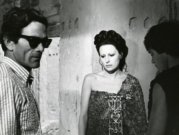 Sul set del film "Edipo Re" - Regia Pier Paolo Pasolini, 1967 - A sinistra, Pier Paolo Pasolini indossa occhiali da sole e rivolge lo sguardo verso destra. Silvana Mangano, al centro, e Franco Citti a destra, osservano in basso a sinistra.