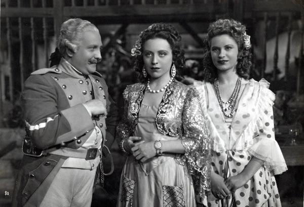 Scena del film "Elisir d'amore" - Regia Amleto Palermi, 1941- A sinistra, un attore non identificato in abiti militari, osserva Margherita Carosio, al centro, e Jone Salinas, a destra.