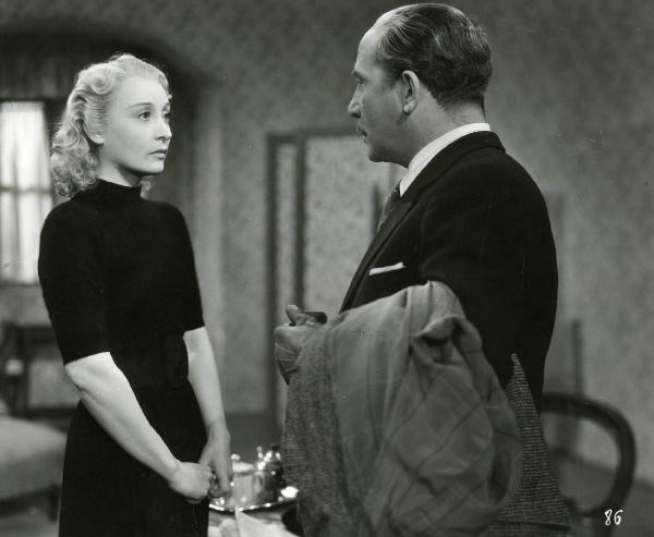 Scena del film "Enrico IV" - Regia Giorgio Pastina, 1943 - Clara Calamai rivolge lo sguardo a Luigi Pavese. L'attore porta una giacca sottobraccio.
