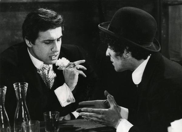 Scena del film "Er più storia d'amore e di coltello" - Regia Sergio Corbucci, 1971 - Adriano Celentano, a sinistra con uno stuzzicadenti in bocca, discute con Ninetto Davoli, a destra.