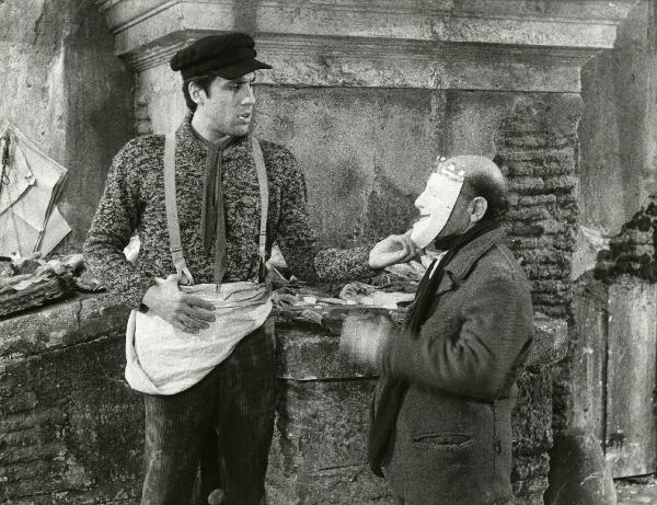 Scena del film "Er più storia d'amore e di coltello" - Regia Sergio Corbucci, 1971 - Adriano Celentano, a sinistra, con la mano destra mentre con la sinistra tocca la maschera che copre il volto dell'attore non identificato a destra.