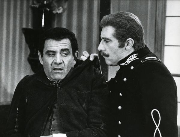 Scena del film "Er più storia d'amore e di coltello" - Regia Sergio Corbucci, 1971 - Romolo Valli, a destra di profilo, afferra la spalla sinistra della giacca di Vittorio Caprioli, a sinistra.