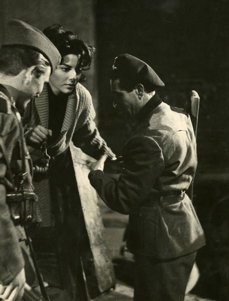 Scena del film "Era notte a Roma" - Regia Roberto Rossellini, 1960 - Giovanna Ralli è sostenuta da due attori non identificati in vesti militari.