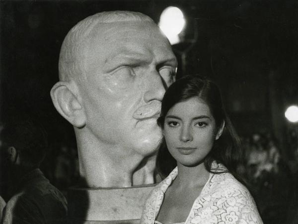 Scena del film "Estate violenta" - Regia Valerio Zurlini, 1959 - Primo piano di Jacqueline Sassard che rivolge lo sguardo verso l'obiettivo mentre, alle sue spalle, si trova una statua in marmo rappresentate il capo di un uomo.