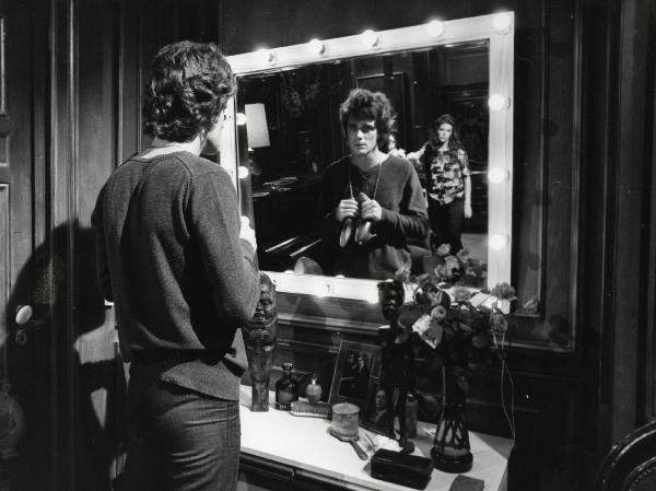 Scena del film "L'etrusco uccide ancora" - Regia Armando Crispino, 1972 - Davanti a uno specchio: un attore non identificato di spalle tiene in mano un paio di scarpe da donna. Riflessa nello specchio Samantha Eggar, lo osserva.