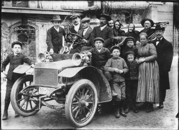Piazza Brembana. Ritratto della famiglia Mostacchi in posa sopra e attorno a un'automobile Adler in occasione delle nozze d'oro di Andrea Mostacchi senior