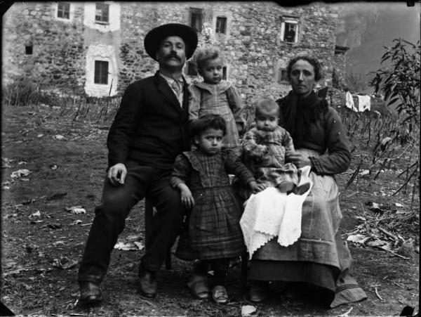 Val Brembana. Ritratto di famiglia in un campo con casa rurale sullo sfondo