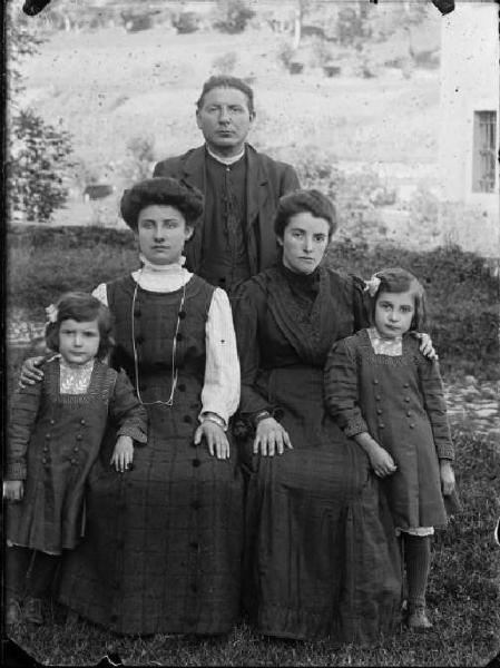 Val Brembana. Ritratto di un gruppo familiare con sacerdote all'esterno di una casa rurale