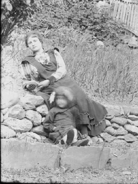 Val Brembana. Ritratto di donna e bambina sedute su un muretto in un campo