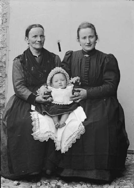 Val Brembana. Ritratto di due donne sedute con bambino piccolo sulle ginocchia