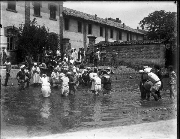 Garlasco - Festa delle mondine - Gruppo di mondine con le gambe immerse nell'acqua - Gruppo di uomini osserva vicino ad un cascinale