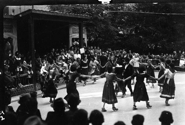 Salice Terme - IX Festa nazionale dell'uva - Parco - Danza di un gruppo di giovani donne in abiti tradizionali - Uomini con strumenti musicali sullo sfondo