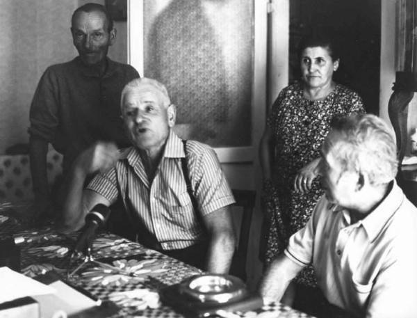 Durante la registrazione. Tre uomini e una donna attorno ad un tavolo in interno di abitazione.