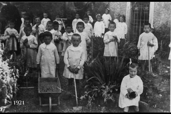 Col rastrello Claudio Salvi, all'asilo. Bambini nel giardino di un asilo con attrezzi.