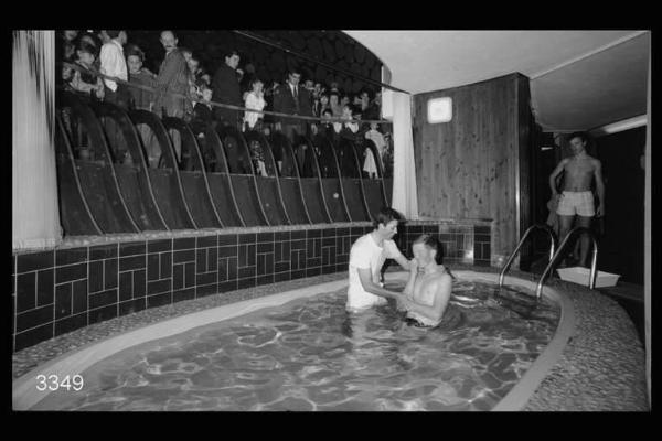 Testimoni di Geova. Battesimo di una persona che viene immersa in una piscina.