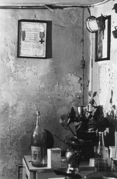 Interno di un'abitazione: oggetti disposti sopra un frigorifero alla parete attestato di onoreficenza di Cavaliere dell'Ordine di Vittorio Veneto.