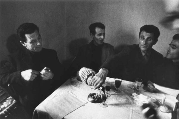 Canto popolare, gruppo di Santa Croce. Canto in osteria: uomini intorno a un tavolo con bicchieri di vino.