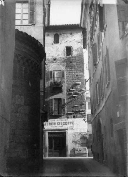 Torre di Ercole e resto della chiesa di San Marco a Brescia. Inquadratura della fronte della torre del Quattrocento adibita ad abitazione e negozio (pizzicheria) sulla sinistra abside romanica.