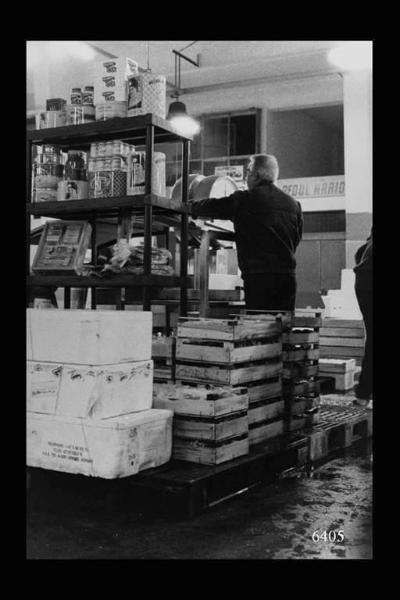 Milano. Via Sammartini 71. Mercato Ittico. Preparazione del mercato; in primo piano, a lato, scaffalatura metallica con scatole in latta di acciughe.