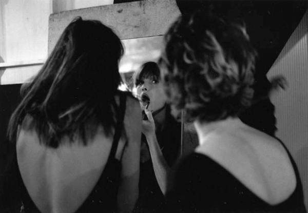 La modella Carla Bruni riflessa in uno specchio mentre si trucca il volto.