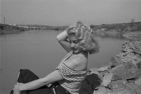 Località non identificata. L'attrice Maria Teresa Vianello ritratta seduta sulla riva di un fiume