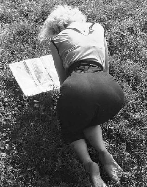 Località non identificata. La giovane attrice Rosalina Neri ritratta, di spalle, su un prato mentre legge una rivista