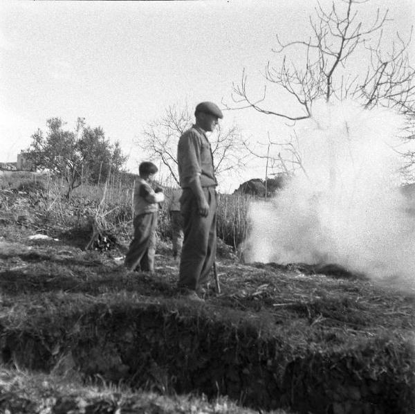 Melissa (Crotone) - Contadino con due bambini in un campo mentre bruciano le sterpaglie