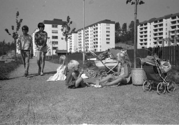 Svezia, Stoccolma - Gruppo di bambini con giocattoli e carrozzine - Sullo sfondo palazzi di periferia
