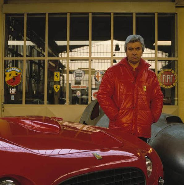 Autofficina macchine sportive - il titolare posa di fianco a una vettura sportiva Ferrari