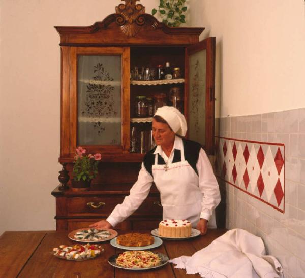 Suor Germana in cucina dispone sul tavolo i cibi da lei preparati