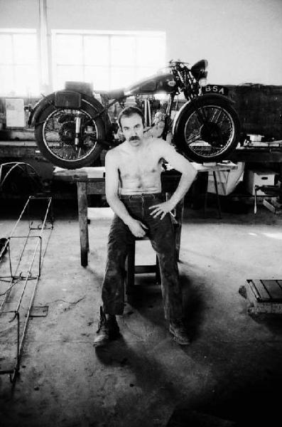 Ritratto maschile - motociclista a torso nudo davanti alla sua motocicletta