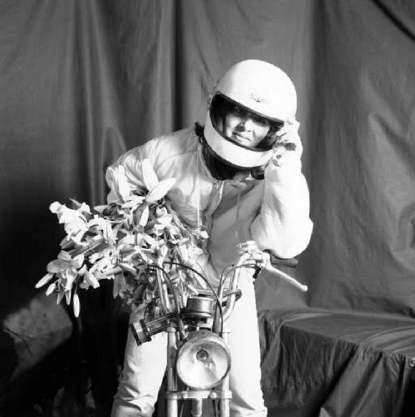 Ritratto femminile - giovane donna sul motorino con il casco e un mazzo di fiori