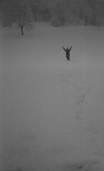 Figura umana in lontananza con le braccia levate nel bagliore della neve