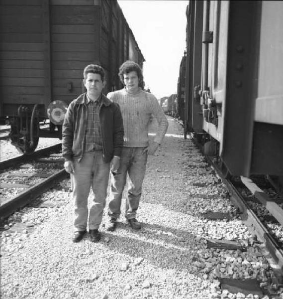 Ritratto di due uomini fra vagoni ferroviari